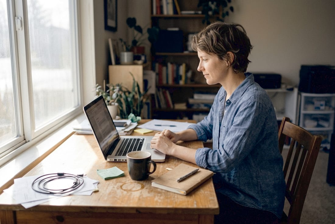 Selbstständige am Laptop am Fenster – mit wenig Aufwand zu einem professionellen Online-Auftritt.